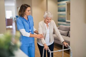 An elder using a walker moves safely through a wide, well-lit hallway with handrails and non-slip flooring.