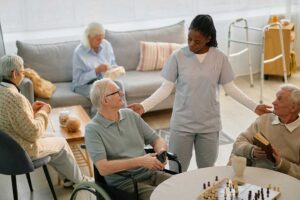 Two seniors chatting over coffee in a sunny, comfortable common area of an assisted living community.