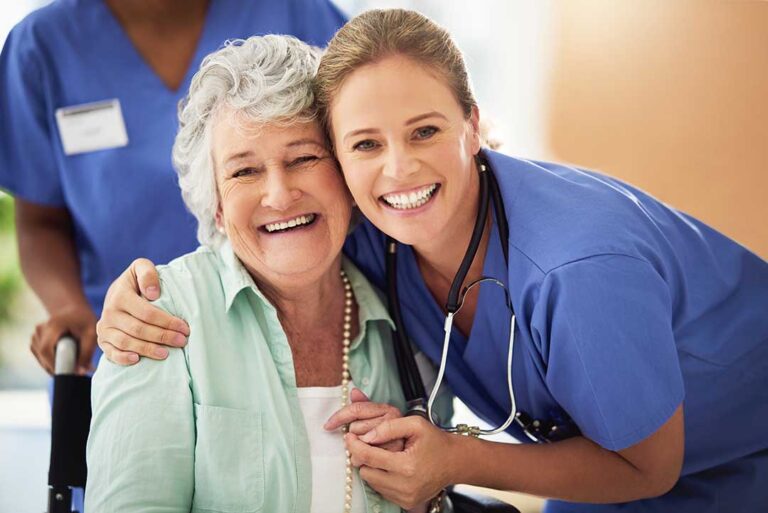 Staff member helps an older resident choose clothing in a bright, tidy assisted living room.